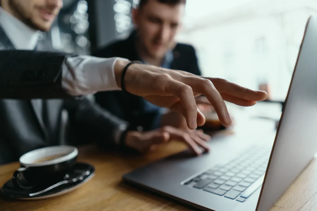 two businessmen pointing laptop screen while discussing 1